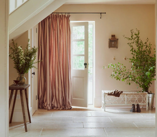 Hallway with rust striped curtains puddling on the floor beside a door