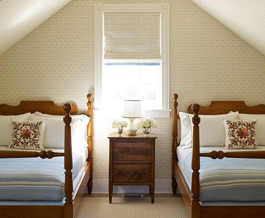 Attic bedroom with a flat fold roman shade on a small window between twin beds